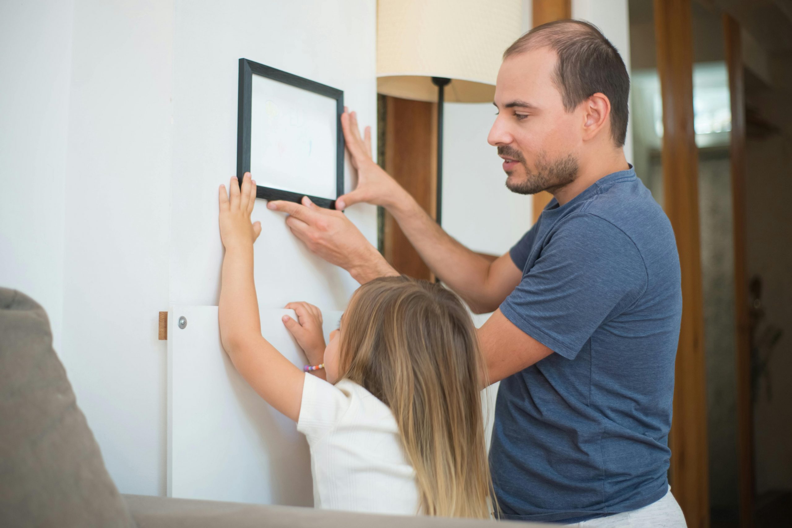 father helping his daughter hang a picture