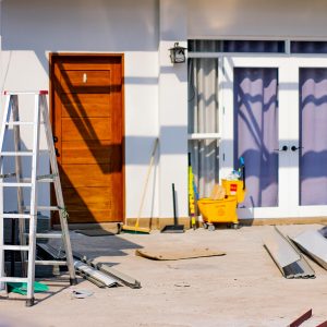 freshly painted house exterior with a ladder leaning against the wall and various construction materials scattered