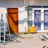 freshly painted house exterior with a ladder leaning against the wall and various construction materials scattered