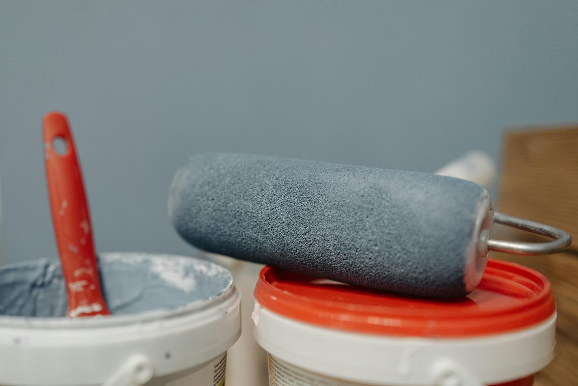 buckets of bluish-gray exterior paint with a paint roller